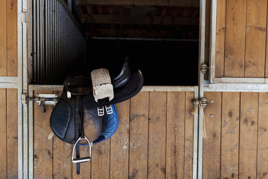 Saddle hanging on door of horse stable