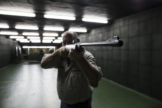 Man aiming with a carbine in an indoor shooting range