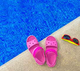 Slippers and sunglasses near the pool. Space for text.