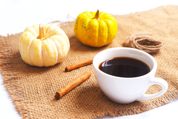 Close up of a cup of coffee with pumpkin and cinnamon on a sackcloth.