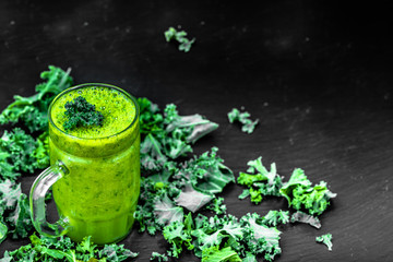 Glass of smoothie with green vegetables, leaves of kale in a jar
