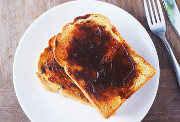 Close up of Australian breakfast with savory spread on a sliced wholewheat toast on a wooden table.