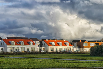 Fototapeta premium Sunshine on houses under a thunder sky