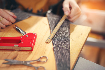 Man upholstering chair in his workshop, measure wooden board