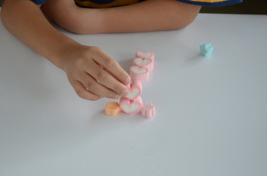 Child hands play jellys on white table