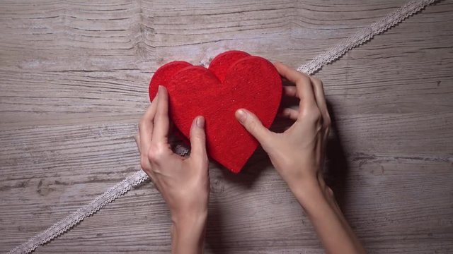 Girl ties up two red hearts with a lacy ribbon, top view. Romance, love, Valentine's day, relationship concepts. 4K video