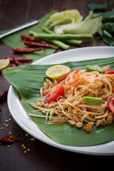Green Papaya Salad (Som tum Thai) on wood table. Green Papaya Salad (Som tum Thai) on wood table. Green papaya salad spicy thai food on banana leaf.  close up of   Som tum Thai menu Asian food.