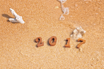 Fototapeta na wymiar Wood number 2017 on beach, happy new year concept and soft wave idea