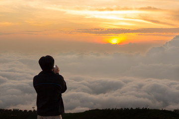 Fototapeta premium Young man traveler taking photo with smartphone at mountains in morning Lifestyle concept, copy space