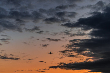 Airplane in the air and sunset sky in background