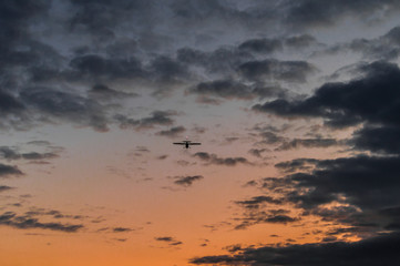 Airplane in the air and sunset sky in background