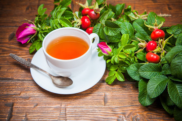 Healthy tea with a dogrose on wooden table