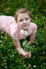 Portrait of a beautiful girl outdoors sitting on grass with flowers