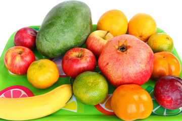 Assorted fruit on a green tray. Colorful sweet aromatic fruits for raw eating or squeezing or preparing smoothie. White background