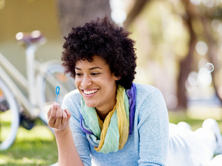 Beautiful woman blowing bubbles in park