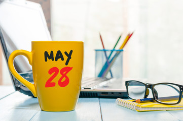 May 28th. Day 28 of month, calendar on morning coffee cup, business office background, workplace with laptop and glasses. Spring time, empty space for text