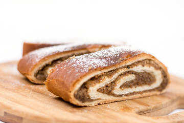 Strudel with walnuts and sugar on the round wooden board