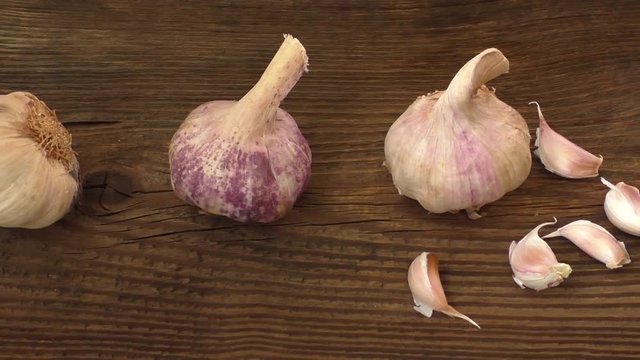 Group of single garlic cloves and a clump of garlic on wooden background
