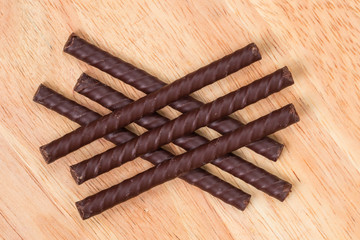 Chocolate sticks lie on a wooden surface. Chocolate dessert. Tasty sweetness.