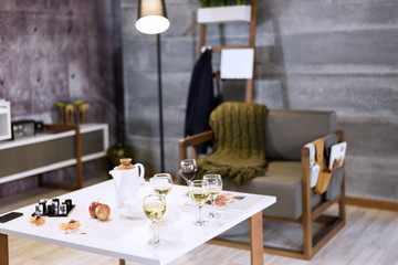 Interior in loft style with glasses of red and white wine on white table.