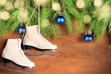 Christmas decoration. Skates and fir branch on wooden background.