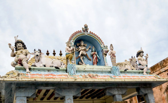 Statues dancing god Shiva and goddess Parvati, Nandi bull and other mythological creatures on a roof of entrance to the ancient Shiva temple of the 18th century, Pondicherry, South India