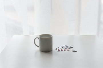 white pills lying next to a glass of water on a wooden table