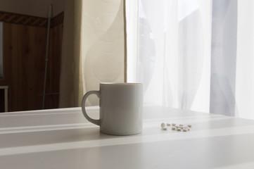 white pills lying next to a glass of water on a wooden table