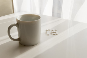 white pills lying next to a glass of water on a wooden table