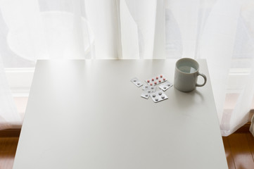 Obraz premium white pills lying next to a glass of water on a wooden table