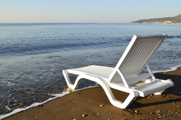 Fototapeta na wymiar Шезлонг, лежак, стоит на пляже, на самом берегу моря. Морской пейзаж.