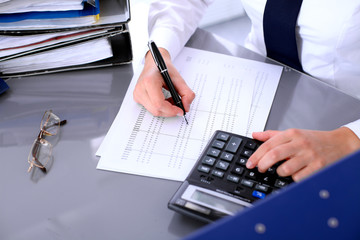 Bookkeeper or female financial inspector  making report, calculating or checking balance. Internal Revenue Service checking financial document. Audit concept.