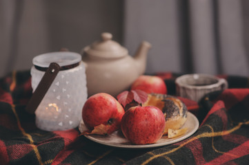 cozy autumn weekend morning at home. Breakfast with cup of tea and bagel with apples on woolen plaid blanket.