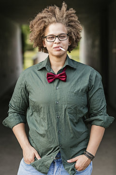 Portrait of lesbian with cigarette wearing glasses and bow tie