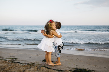 Little girl hugging little boy on the beach