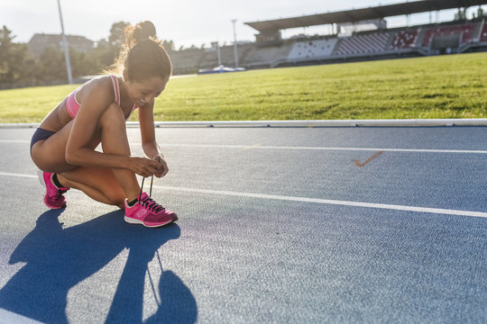 Female athlete tying shoes on race track