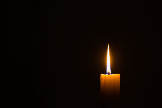 horizontal photo of small candle on dark background with copyspace