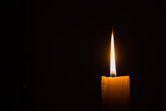 horizontal photo of candle on black background with copyspace on the left
