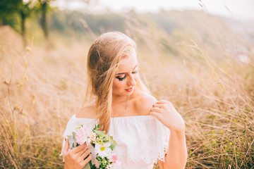 A beautiful young woman sitting near a tree in a sunny day. Beautiful landscape girl holding flowers wreath