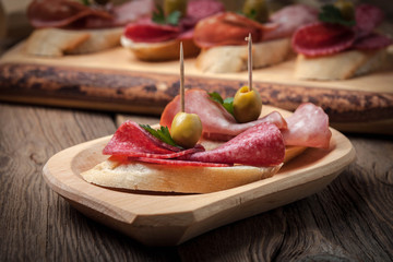 Tapas with sliced sausage, salami, olives and parsley.