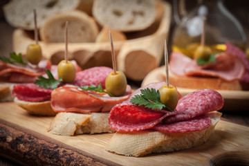 Tapas with sliced sausage, salami, olives and parsley.