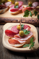 Tapas with sliced sausage, salami, olives and parsley.