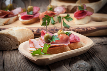 Tapas with sliced sausage, salami, olives and parsley.