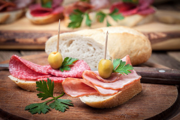 Tapas with sliced sausage, salami, olives and parsley.