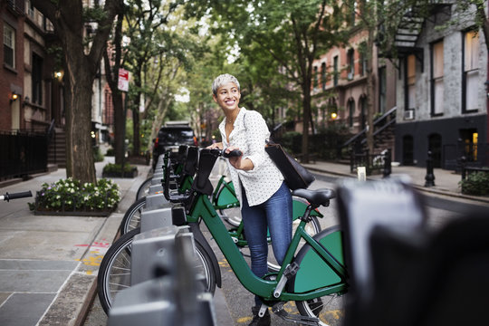 Happy woman looking away while standing by bicycle at parking lot