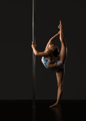 Pole dance. Flexible girl doing vertical split