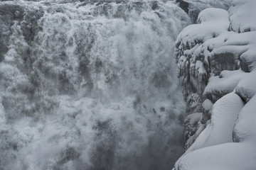 Scenic view of waterfall by snow covered cliff
