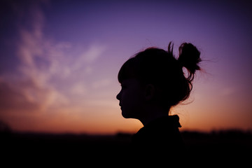 Silhouette girl against dramatic sky during sunset