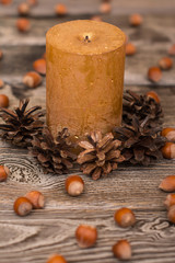 candle, cone, hazelnut on wooden background