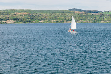 Two people in red rescue vests sailing in a small white boat on